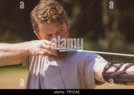 L'uomo praticare il tiro con l'arco a boot camp Foto Stock
