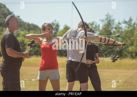 Il trainer di istruire la donna su tiro con l'arco Foto Stock