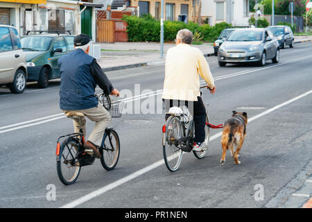 Coppia senior per le biciclette in strada a Santa Teresa di Riva vicino a Messina, Sicilia, Italia Foto Stock