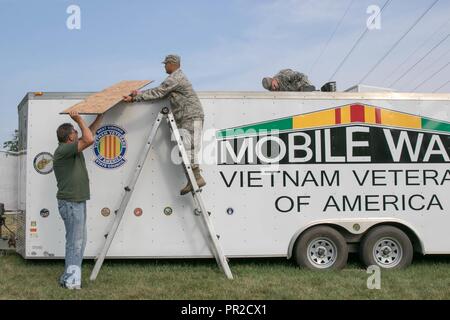 Stati Uniti Senior Airman Anthony Werner, nativo di Weston, W.Va., assegnato come impianti elettrici artigiano per la West Virginia Air National Guard 130Airlift Wing di Charleston, W.Va. e U.S. Il personale dell'esercito Sgt. Jason Dennis, nativo di Parkersburg, W.Va., assegnata come ricognizione non ufficiale incaricato per il West Virginia esercito nazionale Guard 1092nd ingegnere di combattimento del Battaglione Parkersburg, W.Va., assistere John Jones, un veterano del Vietnam e West Virginia membro consiglio sergente di bracci, che lavora il West Virginia membro consiglio Vietnam Veterans of America presentano, con la sostituzione dell'aria cond Foto Stock