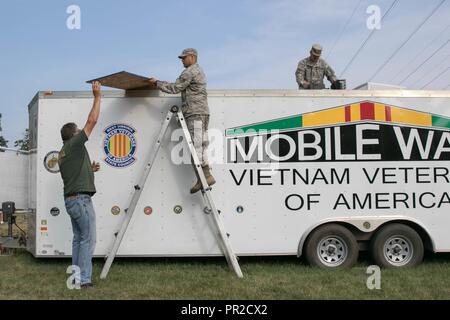Stati Uniti Senior Airman Anthony Werner, nativo di Weston, W.Va., assegnato come impianti elettrici artigiano per la West Virginia Air National Guard 130Airlift Wing di Charleston, W.Va. e U.S. Il personale dell'esercito Sgt. Jason Dennis, nativo di Parkersburg, W.Va., assegnata come ricognizione non ufficiale incaricato per il West Virginia esercito nazionale Guard 1092nd ingegnere di combattimento del Battaglione Parkersburg, W.Va., assistere John Jones, un veterano del Vietnam e West Virginia membro consiglio sergente di bracci, che lavora il West Virginia membro consiglio Vietnam Veterans of America presentano, con la sostituzione dell'aria cond Foto Stock