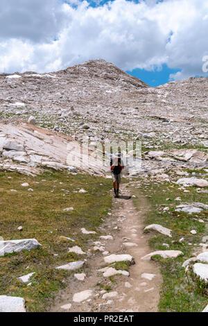 Un adolescente slogs backpacker lungo il John Muir Trail al di sotto di Wanda Lago. John Muir Trail/Pacific Crest Trail; Sequoia Kings Canyon deserto; re possono Foto Stock