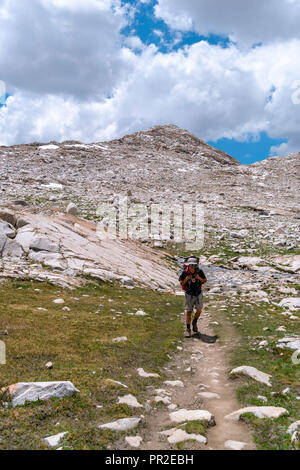 Un adolescente slogs backpacker lungo il John Muir Trail al di sotto di Wanda Lago. John Muir Trail/Pacific Crest Trail; Sequoia Kings Canyon deserto; re possono Foto Stock