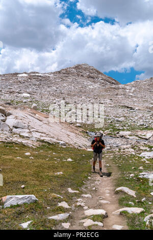 Un adolescente slogs backpacker lungo il John Muir Trail al di sotto di Wanda Lago. John Muir Trail/Pacific Crest Trail; Sequoia Kings Canyon deserto; re possono Foto Stock