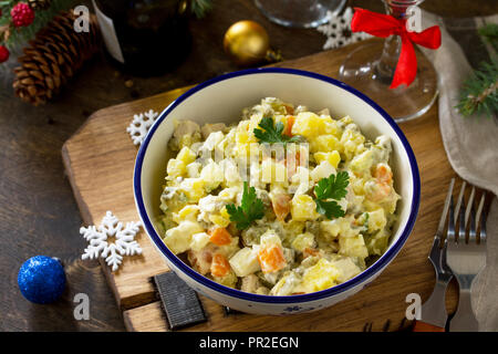 Vacanze inverno insalata. Tradizionale russa Olivier insalata di verdure e pollo su un tavolo di legno. La cucina russa tradizionale. Foto Stock