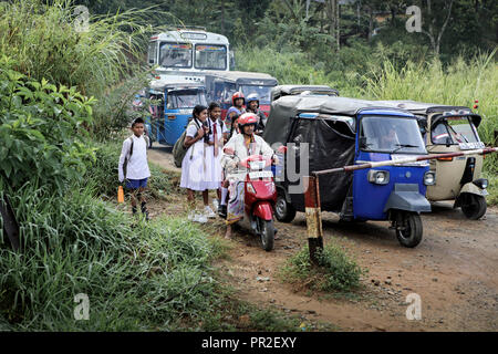 Scolari e rickshaws auto in attesa di attraversamento del treno a Heel Oya, Sri Lanka Foto Stock