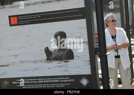 Donna anziana rimane accanto alla scala grande fotografia della statua inondate di leader spirituale indiana Sri Chinmoy sull isola di Kampa a Praga, Repubblica Ceca, raffigurato durante l'alluvione del 2 giugno 2013 dal fotografo documentario Vova Pomortzeff visualizzato in mostra all'aperto dedicato al 2013 inondazioni in Europa sull'isola di Kampa a Praga, Repubblica Ceca. Foto Stock