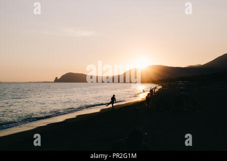 Tramonto scendendo in Fondi (LT), Italia. Presso la spiaggia. Persone appendere fuori. Il salto di pietra, havying divertente, giocando. Foto Stock