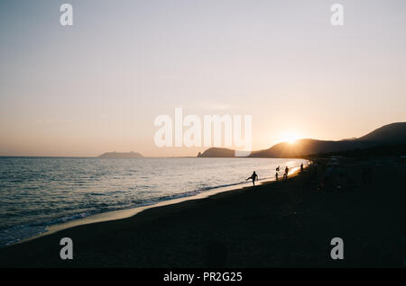 Tramonto scendendo in Fondi (LT), Italia. Presso la spiaggia. Persone appendere fuori. Il salto di pietra, havying divertente, giocando. Foto Stock