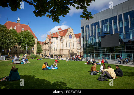 Gli studenti rilassante sull'erba parchi intorno a Manchester Oxford Road Alan Gilbert Learning Commons e Whitworth Hall, Christie's Bistro net-gotico buil Foto Stock