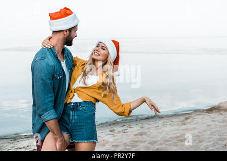 Matura in cappelli di Babbo Natale e abbraccia il divertimento sulla spiaggia Foto Stock