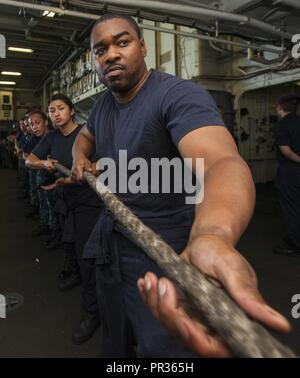 Oceano atlantico (21 luglio 2017) Specialista di intelligence di prima classe Sean Martin heaves una linea intorno con la prima classe Petty Officer Association (FCPOA) durante un rifornimento in mare (RAS) a bordo di un assalto anfibio nave USS Wasp (LHD 1). Vespa è attualmente in corso l'acquisizione di certificazioni in preparazione per il loro prossimo turno di homeport a Sasebo, in Giappone dove sono slated per alleviare la USS Bonhomme Richard (LHD 6) nel 7 ° Flotta area di operazioni. Foto Stock