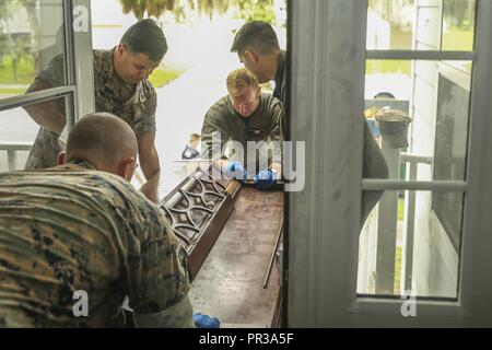 Poliziotti militari rimuovere un pianoforte da una casa danneggiata da un incendio a bordo di Marine Corps reclutare Depot Parris Island, luglio 27. Il Prevosto Marescialli Office ha preso tempo al di fuori della loro giornata per aiutare una famiglia come parte della loro missione di servire e proteggere gli altri. I marines e la polizia militare sono con il PMO, sede e Sede Squadrone imbarcato Marine Corps Air Station Beaufort. Foto Stock