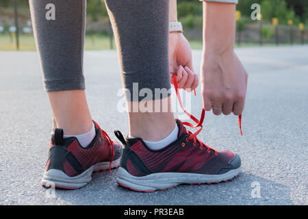 Allacciamento scarpe da corsa. Close-up di donna mani che lace up formatori all'aperto in un parco Foto Stock