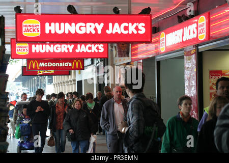 La folla a piedi sotto Hungry Jacks e MCDONALD'S segni in Swanston Street, Melbourne, Victoria, Australia Foto Stock