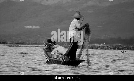La pesca tradizionale con net e lunga coda di barca sul Lago Inle, Myanmar. Una gamba sola tecnica di canottaggio. Foto Stock