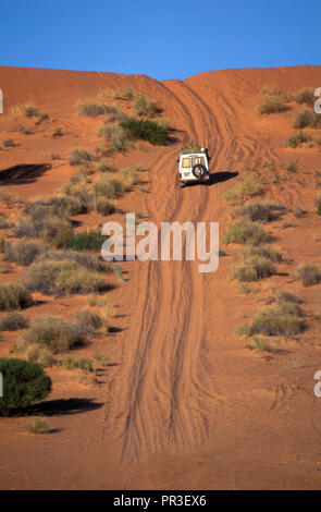 Un veicolo a 4 ruote motrici rende il modo oltre le dune di sabbia rossa su un Outback sterrato, Territorio del Nord, l'Australia. Foto Stock