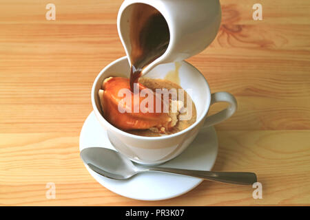 Versando una brocca di acqua calda di caffè espresso sulla coppa di gelato alla vaniglia per un aromatico e gustoso Affogato Foto Stock