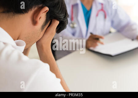 Medico donna hanno la discussione con un paziente uomo che ricopre la faccia con la mano. Medicina e cure sanitarie concetto. Il medico e il paziente. Foto Stock