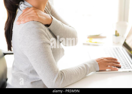 Closeup donna con mani tenendo il suo dolore alla spalla. Sindrome da ufficio e health care concetto. Foto Stock