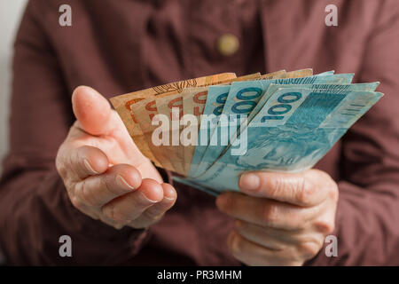 Valuta brasiliana, il denaro dal Brasile. Vista frontale della vecchia donna di mano le bollette di manipolazione. Foto Stock