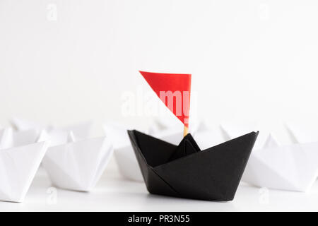 Il concetto di leadership. carta rossa nave piombo tra il bianco. Un leader ship conduce alle altre navi. Foto Stock