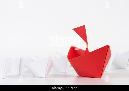 Il concetto di leadership. carta rossa nave piombo tra il bianco. Un leader ship conduce alle altre navi. Foto Stock