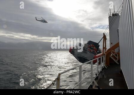 Una stazione di aria Kodiak MH-60 elicottero Jayhawk transita al di sopra del guardacoste Healy nel Chukchi mare al largo della costa di Alaska, 28 luglio 2017. Per 150 anni, Guardia costiera la capacità di proteggere i cittadini americani e gli interessi in Alaska e acque artiche è cresciuto a fianco di Alaska il ruolo sempre più determinante nel commercio globale e di esplorazione artica e la sovranità nazionale. Stati Uniti Coast Guard Foto Stock