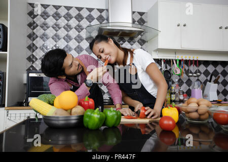 Felice e sorridente coppia giovane la cottura di alimenti in cucina a casa Foto Stock