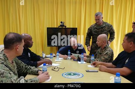 ROTA, Repubblica della Mariana Islands settentrionale - Navy Adm posteriore. Brad Cooper, sinistra, Marine Corps Col. Robert "Bams" Brodie, e il tenente Col. Christopher Johnson, in piedi, discutere il supporto della difesa delle autorità civili con l'on. Ralph Torres, governatore del Commonwealth delle Isole Marianne Settentrionali Isole e i rappresentanti del governo federale Emergency Management Agency durante un incontro presso il locale ufficio del governo, Sett. 11, 2018. I membri del servizio dal comando Indo-pacifico stanno fornendo il Dipartimento della Difesa supportano la FEMA, e lavorando con Guam e la CNMI's civile e funzionari locali per Foto Stock