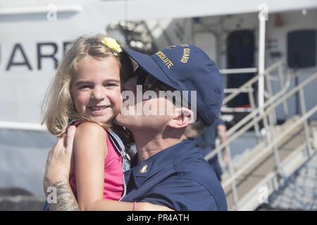 Chief Petty Officer Nathan Finley, un membro di equipaggio a bordo del guardacoste risoluta, baci di sua figlia Skylar Finley, per la prima volta in 59 giorni a San Pietroburgo, Florida, Domenica, Settembre 9, 2018. La risoluta equipaggio tornò a homeport dopo il pattugliamento nei Caraibi per quasi due mesi. Foto Stock