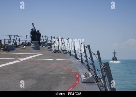 Oceano Indiano (sett. 13, 2018) marinai sollevare il martinetto personale sul castello di prua del Arleigh Burke-class guidato-missile destroyer USS Michael Murphy (DDG 112) come vele al fianco di HMAS Newcastle (FFG 06) In seguito alla fase di mare della Australian esercizio, Kakadu 2018. Michael Murphy sta partecipando in esercizio Kakadu 2018 per migliorare la sicurezza marittima le competenze con le nazioni partecipanti mettendo in evidenza il valore della condivisione delle informazioni e di coordinamento multilaterale. Foto Stock