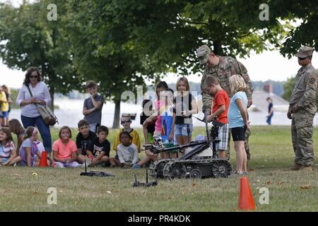 I soldati dell'Ingegnere xli Battaglione, 2° Brigata Team di combattimento, decimo Montagna divisione, insegnare ai bambini locali di operare contati improvvisato dispositivo esplosivo robot di rilevazione durante una visualizzazione statica, evento in astucci Harbour, New York, 14 settembre 2018. Gli ingegneri hanno mostrato le proprie competenze e le attrezzature per la Comunità a seguito di una formazione Helocast esercizio nelle vicinanze del fiume nero Bay. Foto Stock