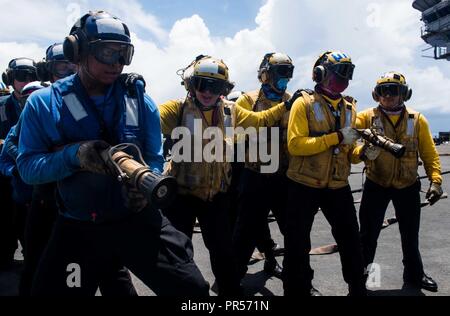 Mare delle Filippine (17 settembre 2018) marinai contro un aereo simulato il fuoco come parte di una massa casualty drill sul ponte di volo della Marina è distribuita portaerei USS Ronald Reagan (CVN 76) durante la Valiant scudo 2018. La biennale, SOLO NEGLI STATI UNITI, campo-esercizio di formazione si concentra sull'integrazione di formazione congiunta tra Stati Uniti Navy, Air Force e Marine Corps. Questo è il settimo esercizio nel Valiant scudo serie che ha avuto inizio nel 2006. Foto Stock