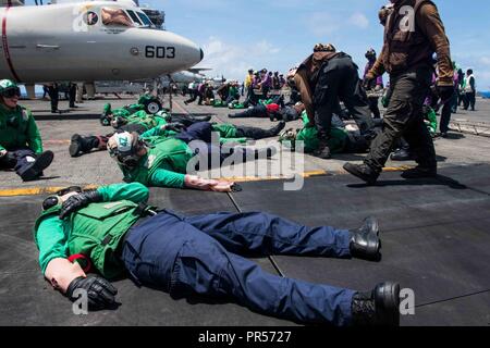 Mare delle Filippine (17 settembre 2018) marinai giocare i ruoli delle persone ferite come parte di una massa casualty drill sul ponte di volo della Marina è distribuita portaerei USS Ronald Reagan (CVN 76) durante la Valiant scudo 2018. La biennale, SOLO NEGLI STATI UNITI, campo-esercizio di formazione si concentra sull'integrazione di formazione congiunta tra Stati Uniti Navy, Air Force e Marine Corps. Questo è il settimo esercizio nel Valiant scudo serie che ha avuto inizio nel 2006. Foto Stock