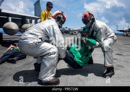 Mare delle Filippine (17 settembre 2018) marinai del crash e equipaggio di soccorso rimuovere la simulazione di una vittima come parte di una massa casualty drill sul ponte di volo della Marina è distribuita portaerei USS Ronald Reagan (CVN 76) durante la Valiant scudo 2018. La biennale, SOLO NEGLI STATI UNITI, campo-esercizio di formazione si concentra sull'integrazione di formazione congiunta tra Stati Uniti Navy, Air Force e Marine Corps. Questo è il settimo esercizio nel Valiant scudo serie che ha avuto inizio nel 2006. Foto Stock
