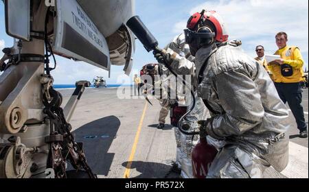 Mare delle Filippine (17 settembre 2018) marinai del crash e recupero equipaggio eseguire revisione su un aereo simulato il fuoco come parte di una massa casualty drill sul ponte di volo della Marina è distribuita portaerei USS Ronald Reagan (CVN 76) durante la Valiant scudo 2018. La biennale, SOLO NEGLI STATI UNITI, campo-esercizio di formazione si concentra sull'integrazione di formazione congiunta tra Stati Uniti Navy, Air Force e Marine Corps. Questo è il settimo esercizio nel Valiant scudo serie che ha avuto inizio nel 2006. Foto Stock