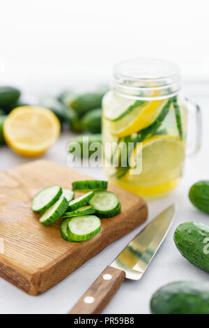 Focus su fette di cetriolo. Summer cocktail cetriolo limonata. Acqua rinfrescante con cetriolo, menta e limone su sfondo grigio. Bibita salutare e detox concetto. Spazio di copia Foto Stock