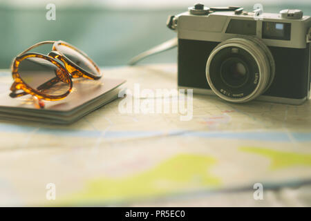 Vintage cinepresa, occhiali da sole e un passaporto su una mappa - Concetto di viaggio, soft focus Foto Stock