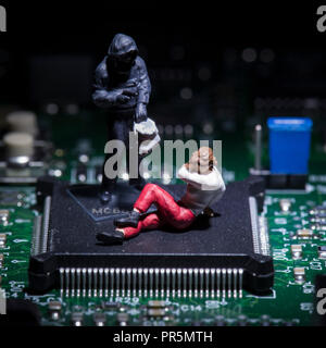 figure giocattolo in cima a un chip per computer - concetto di cyber crimine Foto Stock