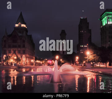 Syracuse, New York, Stati Uniti d'America. Settembre 29, 2018. Clinton Square nel centro cittadino di Syracuse, NY, con fontana e stagno riflettente nelle ore notturne Foto Stock