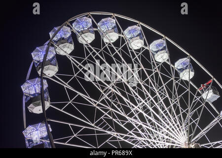 Un grande spiazzo ferris o grande giro di ruota illuminata e illuminato con luci contro il cielo notturno Foto Stock