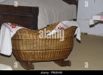 Un piccolo antiquariato culla in legno su gambe di legno per un piccolo bambino.vecchia culla di legno in una casa in paese Foto Stock