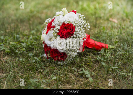 Bouquet di fiori in autunno verde erba con due anelli d oro su di esso. Foto Stock