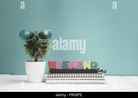 WEEKEND lettere testo e carta per notebook e un po' di decorazione albero in vaso bianco su sfondo di legno, ciao weekend Concetto di vacanza idea. Foto Stock