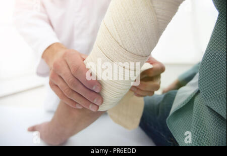 Ortopedico applicando un bendaggio sulla mano del paziente in clinica Foto Stock