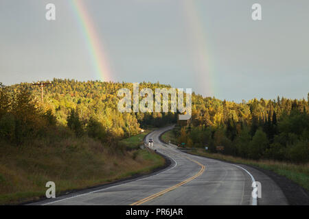 Arcobaleno doppio sopra la strada curva attraverso colline nel nord del Minnesota durante l'autunno Foto Stock