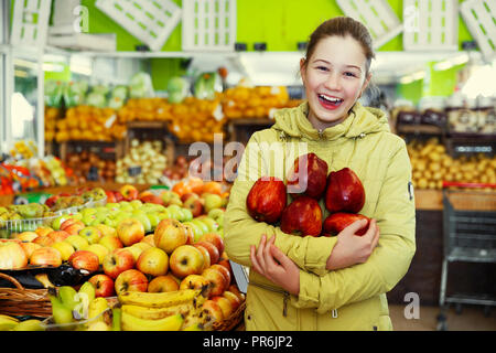 Ritratto di felice bambina con grandi mele rosse nelle mani nel mercato della frutta interno Foto Stock