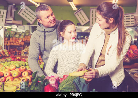 Famiglia felice con la figlia preteen acquistare banane mature nel negozio di frutta Foto Stock