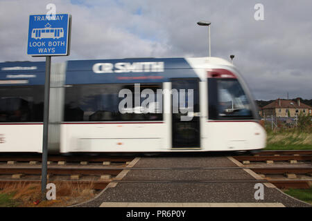 Un tram di Edimburgo passa da un segno di attenzione come si fa il suo modo al di sopra di un attraversamento pedonale punto Foto Stock
